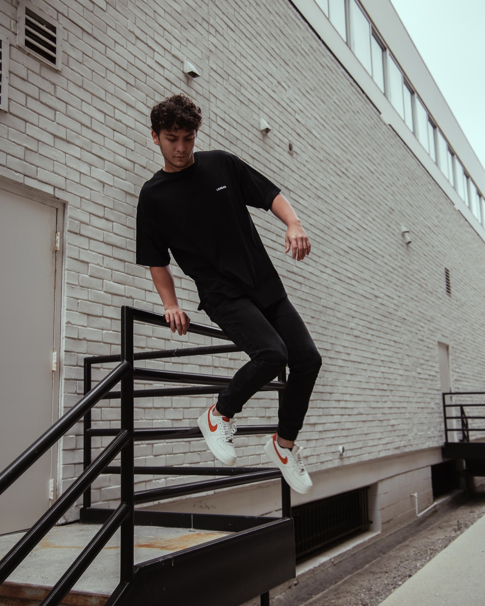 man in black crew neck t-shirt and black pants jumping on stairs